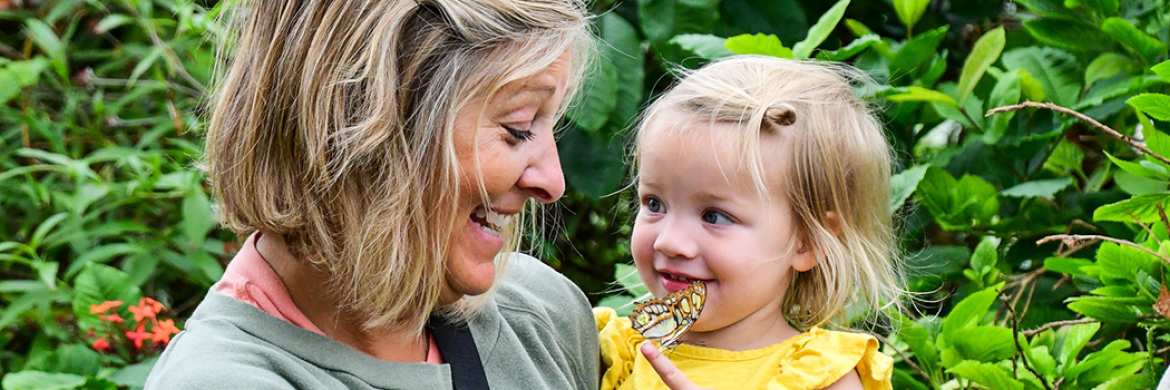 Woman holding baby girl with a butterfly on her finger