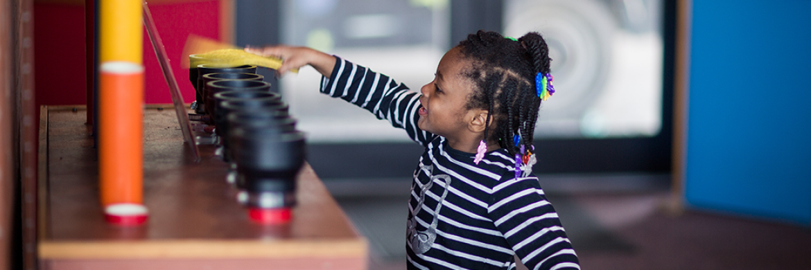 Young girl playing with an interactive exhibit at the Grout Museum